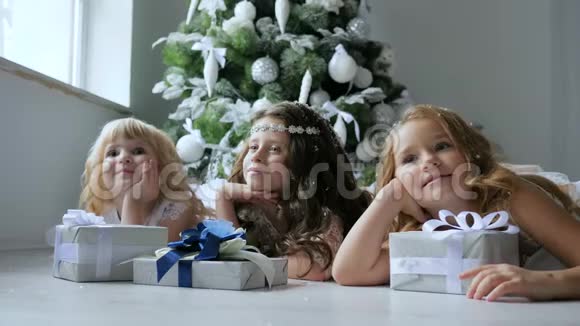 圣诞节躺在白色地板上的女朋友的画像礼物放在装饰过的圣诞树旁边视频的预览图