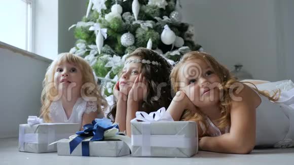 庆祝气氛卷发的小女朋友们在圣诞树的背景上梦想着礼物视频的预览图
