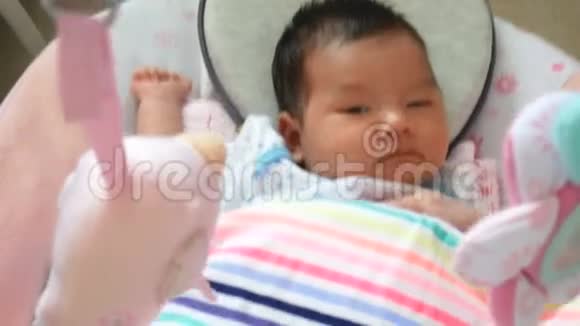 4K镜头可爱的亚洲宝宝睡意朦胧躺在摇篮里视频的预览图