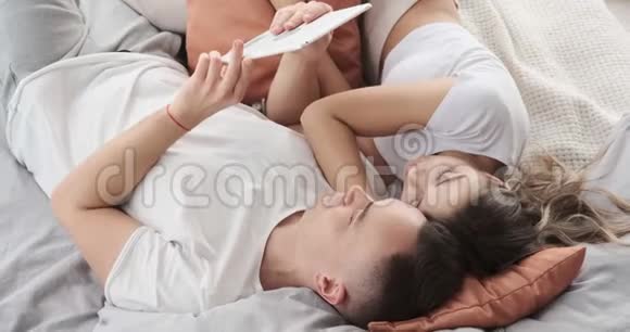 年轻夫妇在床上使用数码平板电脑视频的预览图