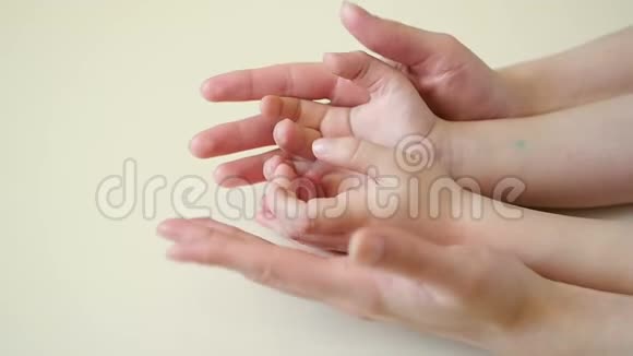 母亲的手抚摸着孩子的手特写母亲的手慢慢地抚摸着孩子的手视频的预览图