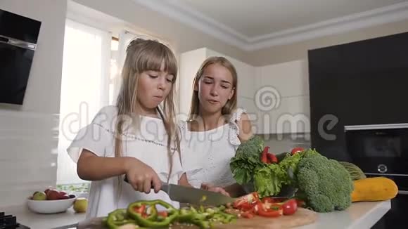 两个迷人的姐妹做蔬菜切片女孩切辣椒准备蔬菜沙拉健康食品视频的预览图