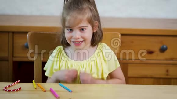 小女孩穿着黄色的连衣裙用蜡笔在纸上画画视频的预览图