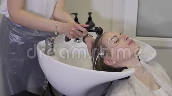 在美容院洗金发女人美丽的女孩在美容院洗头发视频的预览图