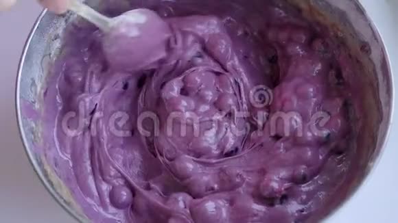 女用勺子在不锈钢碗里准备蓝莓派的面团视频的预览图