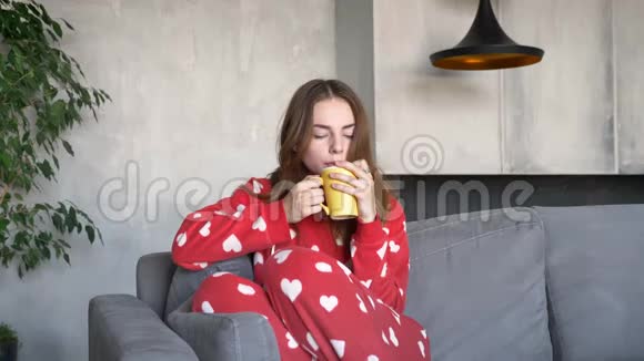 美丽的年轻女子姜发喝着咖啡坐在现代客厅的沙发上严肃而忧郁视频的预览图