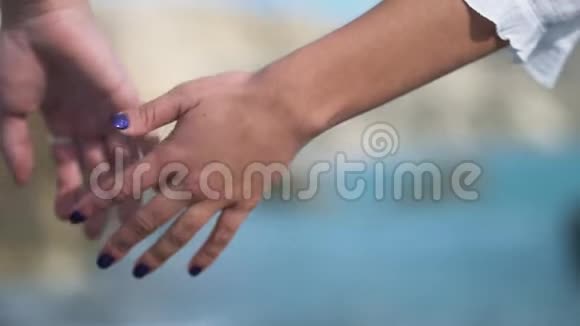 在阳光明媚的海滩上一对迷人的夫妇紧紧地挽着手走着联盟关爱伙伴慢动作视频的预览图