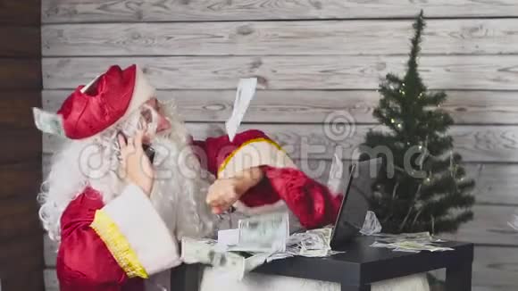 圣诞老人在手机上说话在电脑上工作钱落在他身上慢动作视频的预览图