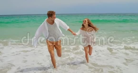 高加索夫妇在海滩上奔跑的正面景色视频的预览图