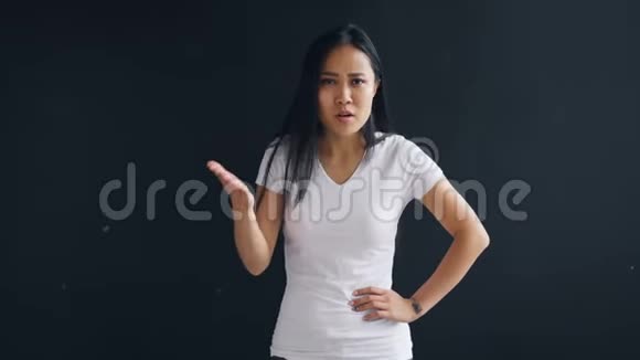 愤怒的亚洲女人站在黑色背景下说话和手势表达负面情绪的肖像视频的预览图