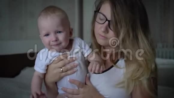 神经衰弱紧张的年轻母亲头痛双手抱着婴儿坐在床上视频的预览图