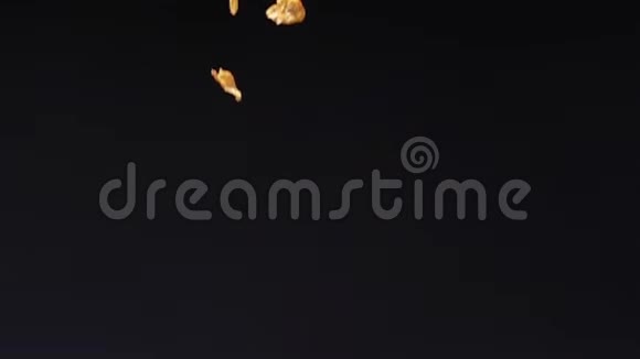 脆黄的玉米片在黑色背景下落在地上视频的预览图