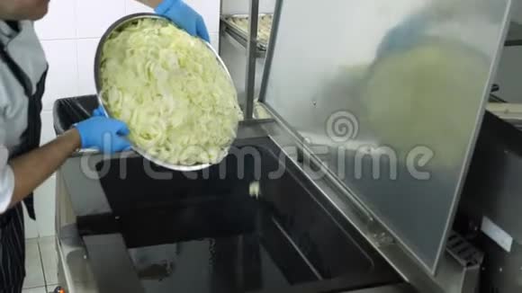特写镜头一个戴着手套的厨师把许多新鲜的切碎的洋葱放在一个大的工业煎锅上烤煮视频的预览图