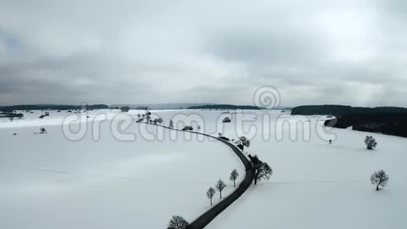 在一个阴天的冬天一条孤独的道路在雪地上蜿蜒曲折无人机在马路上街上视频的预览图