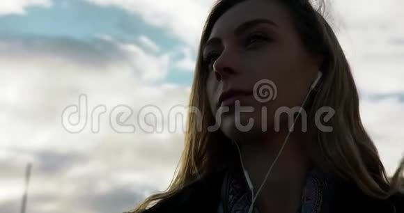 斯德哥尔摩一个多风的中心一位年轻女子在听耳机音乐视频的预览图