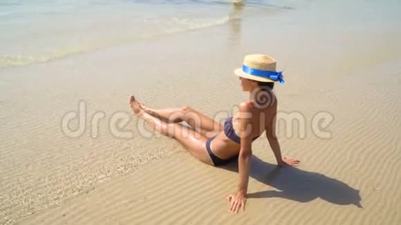 夏季生活方式高清视频漂亮年轻晒黑的女人戴帽子享受生活坐在海滩上时间到了视频的预览图