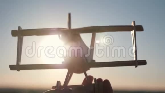 的手拿着一架木飞机对着夕阳视频的预览图