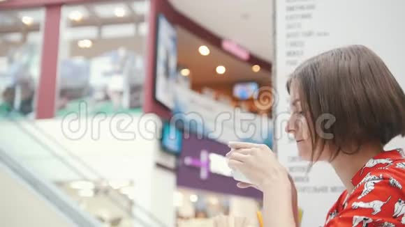 一个女孩在咖啡店喝咖啡拿着杯子视频的预览图