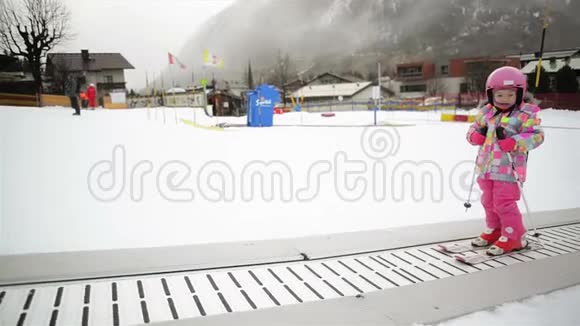 冬季户外运动中的小女孩呆在滑雪传送带上孩子开始滑雪了度假村快乐滑雪体验视频的预览图