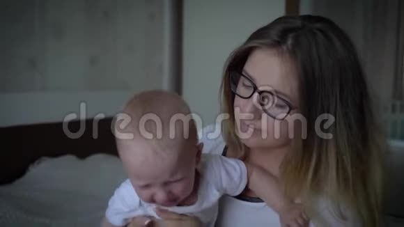偏头痛年轻的母亲头痛手里握着哭泣的孩子视频的预览图