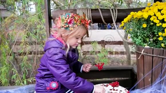 女孩用红色浆果装饰烤馅饼万圣节准备戴着树叶花环视频的预览图