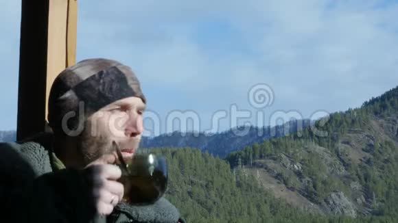 站在观景台上看山喝大杯咖啡或茶的长胡子的孤独男子4公里视频的预览图