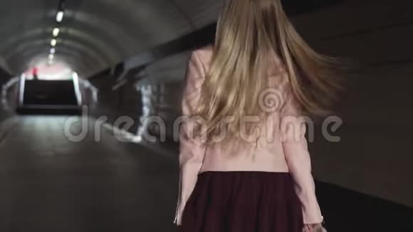夕阳下穿着粉色夹克的迷人少女穿过隧道视频的预览图