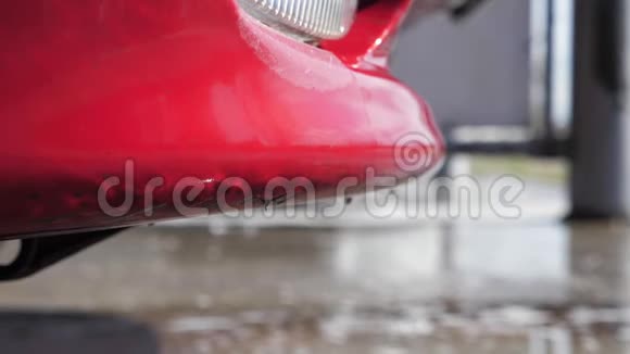 水和泡沫洗涤剂从一辆红色洗过的车中排出视频的预览图