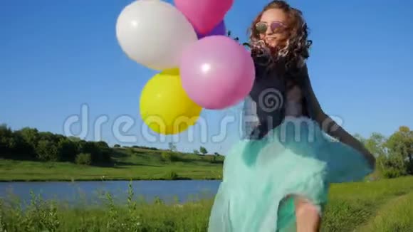 微笑开朗的女孩头发上戴着彩色的卡尼卡龙手臂上戴着球花时间在洛城附近的大自然上视频的预览图