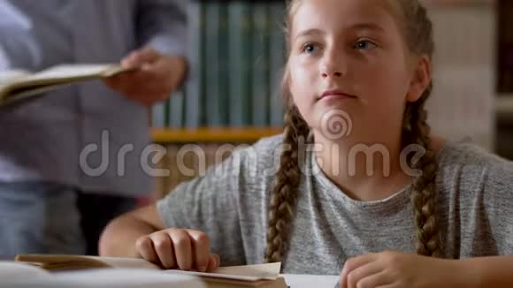 可爱的女孩坐在图书馆的一张桌子旁视频的预览图