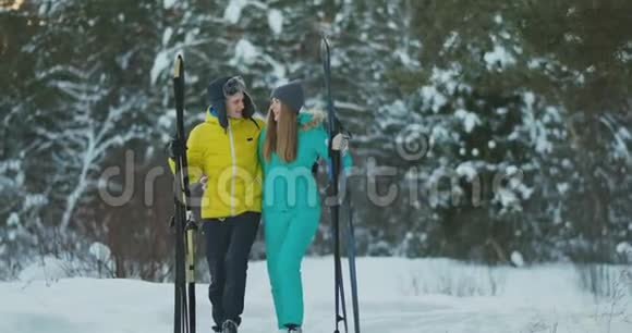可爱的男人和女孩在冬天的森林里缓慢地滑雪微笑着看着对方视频的预览图