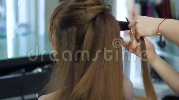 用手和梳子形成头发链用于头发造型发型师长着一个时髦的节日发型视频的预览图