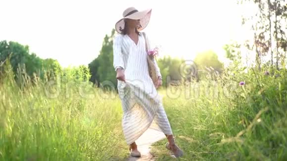 戴着牙套的女人在田野上的夕阳上微笑穿着浪漫的连衣裙会飞的头发室外视频的预览图