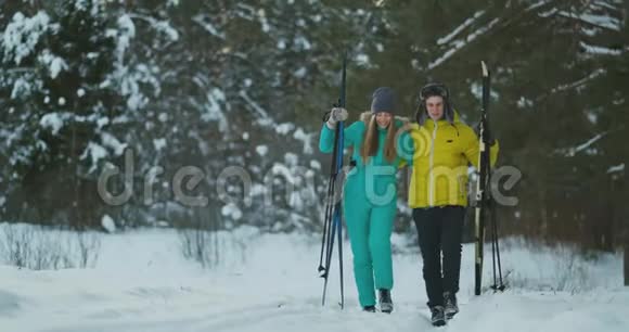 一对活跃的年轻夫妇在白雪皑皑的冬林中享受滑雪的完整肖像集中在微笑的女人面前视频的预览图