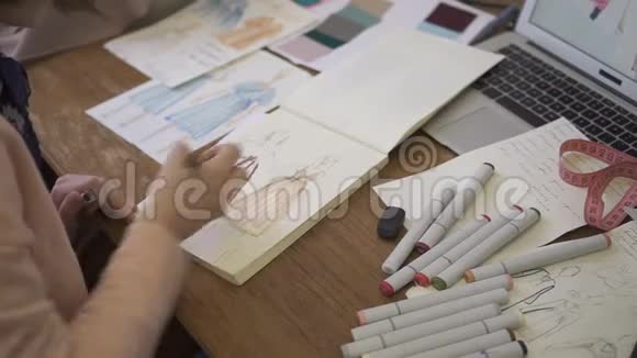 一位年轻的时装设计师正在她的工作室里画一幅新模特的草图视频的预览图