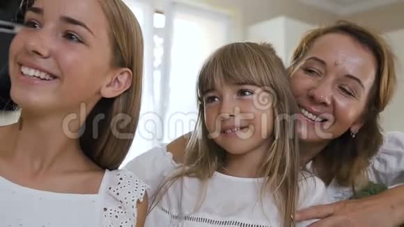一个幸福家庭的肖像谁做自拍在智能手机上拍照时在厨房做饭妈妈和她视频的预览图