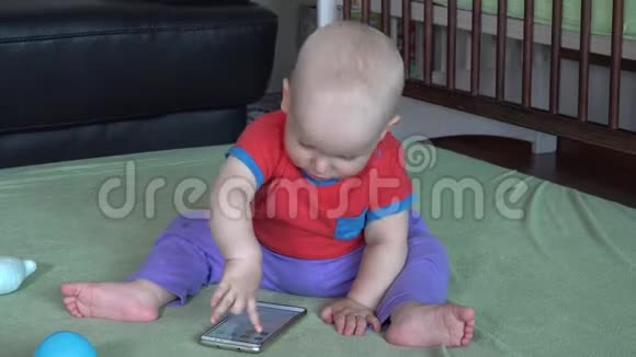 可爱的学步男孩在家玩智能手机视频的预览图