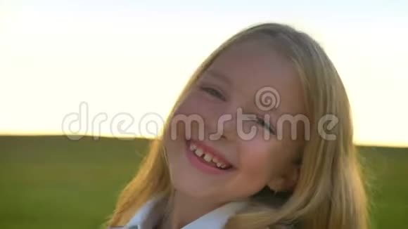 快乐的金发小女孩在镜头前笑着背景是日落时的麦田欢快快乐视频的预览图