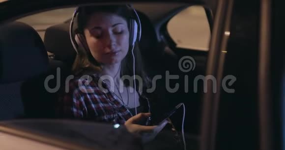 女乘客在车里用立体声耳机听音乐视频的预览图