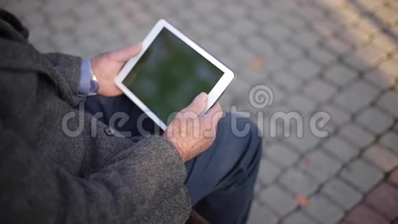 在外面用平板电脑把一个年长的男人锁起来坐在长凳上用平板电脑的老人的后景视频的预览图