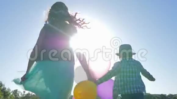 快乐的孩子手牵着彩色气球在蓝天上跳跃视频的预览图