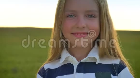 美丽的金发小女孩对着镜头微笑转过头去站在麦田上快乐而又快乐视频的预览图