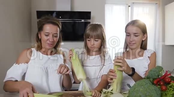 一位年轻的白种人妇女和两个穿着白色衣服的女儿正在打扫卫生吮吸和准备做饭视频的预览图