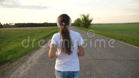 女孩晚上在路上慢跑女孩参加体育活动用耳机听音乐视频的预览图