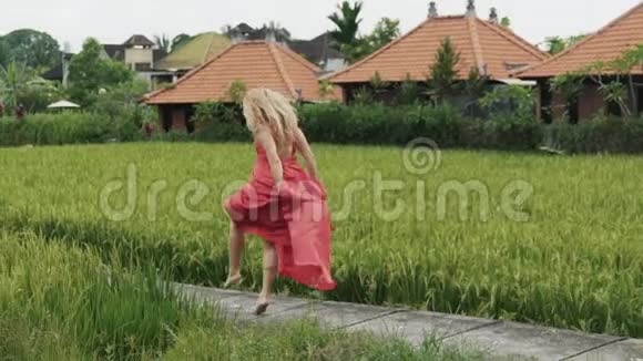 慢镜头拍摄美丽的少女轻松地独自在稻田上跳舞无拘无束地移动做着细绳视频的预览图