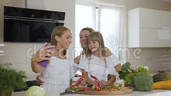 两个可爱的姐妹在家里做饭的时候亲吻他们心爱的迷人的母亲的肖像视频的预览图