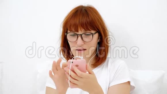 年轻有魅力的女性一边看着智能手机一边用手机发短信给她的朋友白色背景视频的预览图
