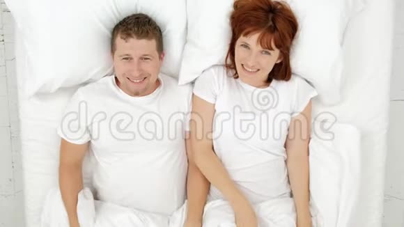 微笑的夫妇在床上玩得很开心躲在毯子下面看着镜头视频的预览图