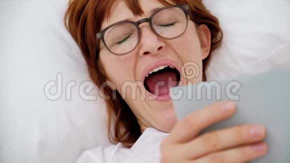 女孩拿着一本书躺在床上打哈欠近点视频的预览图