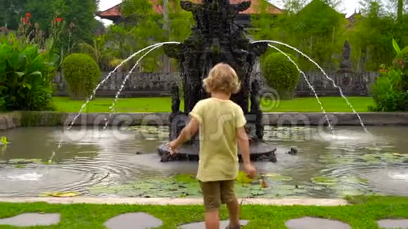 一个小男孩在巴厘岛塔曼阿云寺喷泉周围奔跑的慢镜头视频的预览图